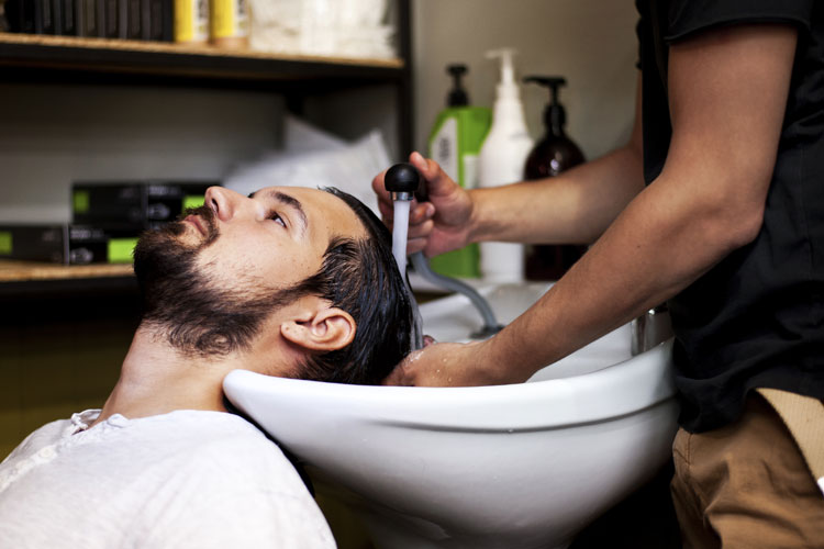 Mann wird beim Friseur der Kopf gewaschen